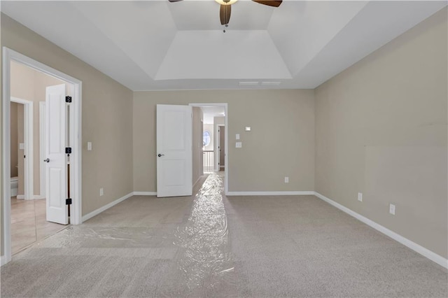 spare room featuring a tray ceiling, ceiling fan, and light colored carpet