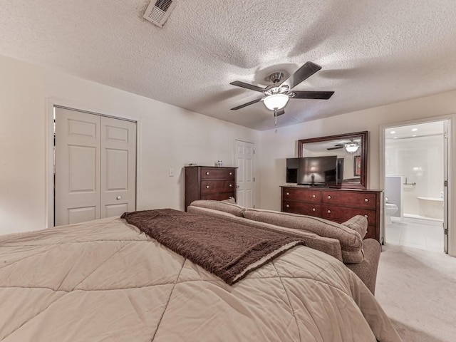 carpeted bedroom with ceiling fan, ensuite bath, and a textured ceiling