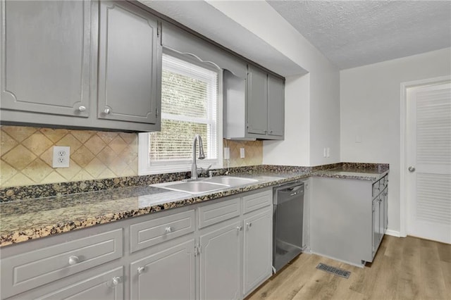 kitchen featuring gray cabinets, tasteful backsplash, sink, stainless steel dishwasher, and light hardwood / wood-style flooring