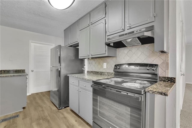 kitchen featuring black electric range oven, light hardwood / wood-style flooring, stainless steel refrigerator, gray cabinets, and backsplash