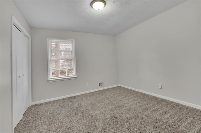 empty room with carpet floors and a textured ceiling