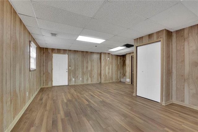 basement with wood-type flooring, a paneled ceiling, and wooden walls