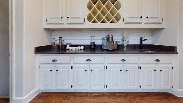 bar featuring sink, white cabinetry, dark wood-type flooring, and backsplash