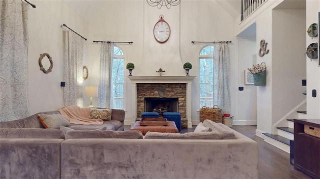 living room featuring dark hardwood / wood-style flooring, a stone fireplace, and a high ceiling