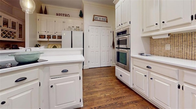 kitchen with white cabinets, ornamental molding, double oven, backsplash, and dark wood-type flooring