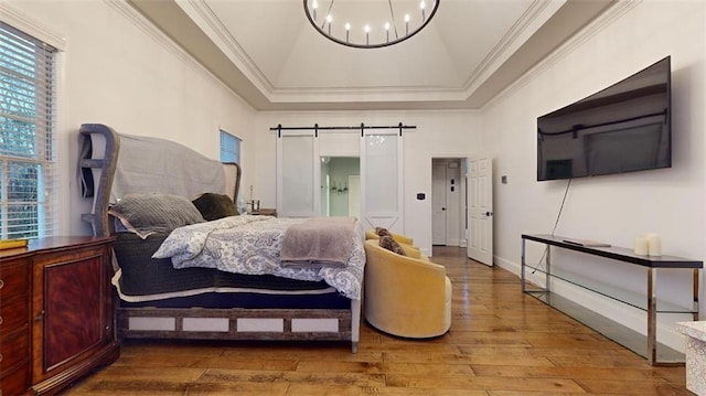 bedroom featuring ornamental molding, hardwood / wood-style floors, a chandelier, and a barn door