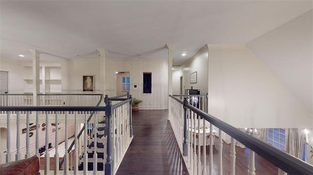 corridor with dark hardwood / wood-style flooring, ornate columns, and ornamental molding