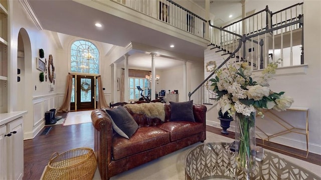 living room with hardwood / wood-style flooring, a notable chandelier, crown molding, and a high ceiling