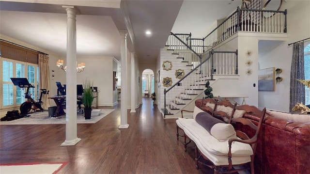 foyer entrance with hardwood / wood-style flooring, a notable chandelier, crown molding, and ornate columns