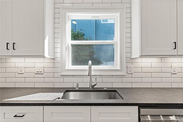 kitchen with stainless steel dishwasher, a sink, white cabinetry, and decorative backsplash