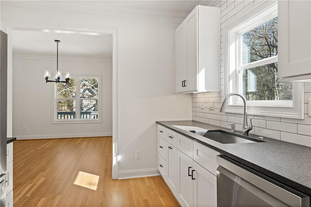 kitchen featuring a sink, dark countertops, ornamental molding, and stainless steel dishwasher