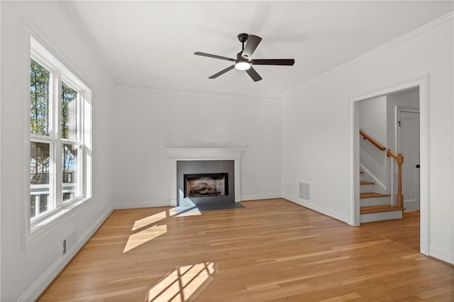 unfurnished living room featuring stairway, plenty of natural light, a fireplace with flush hearth, and light wood-style flooring