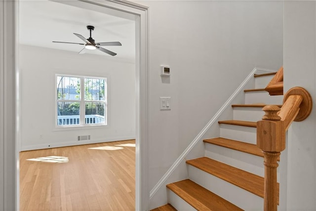 stairs with baseboards, ceiling fan, visible vents, and wood finished floors