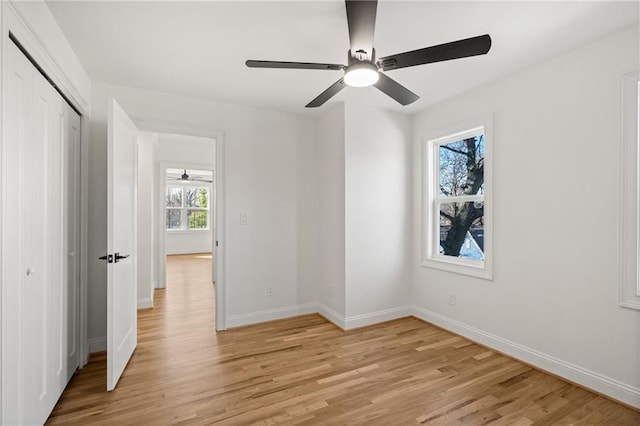 unfurnished bedroom with a closet, baseboards, ceiling fan, and light wood finished floors