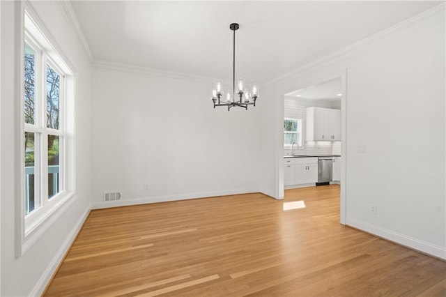 unfurnished dining area featuring baseboards, ornamental molding, visible vents, and light wood-style floors