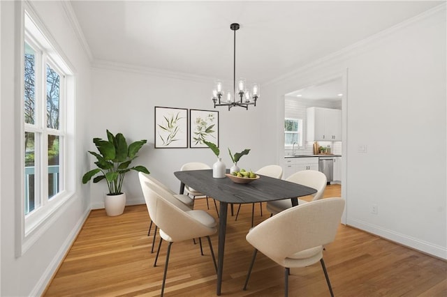 dining area featuring ornamental molding, light wood finished floors, a chandelier, and baseboards