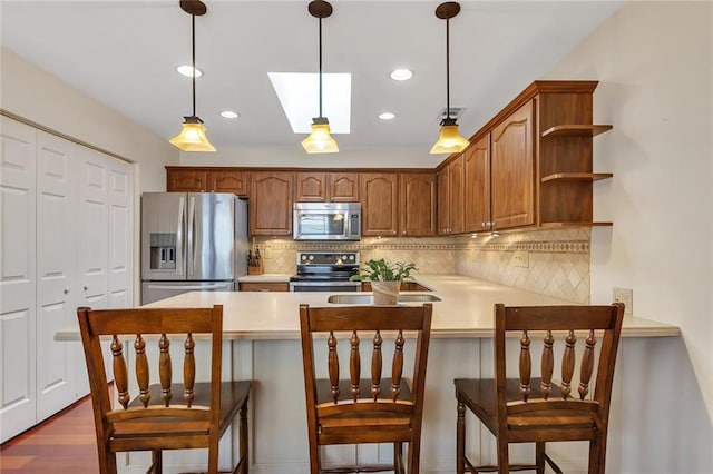 kitchen featuring light countertops, decorative backsplash, a peninsula, hanging light fixtures, and stainless steel appliances