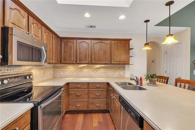 kitchen featuring visible vents, pendant lighting, a sink, wood finished floors, and appliances with stainless steel finishes