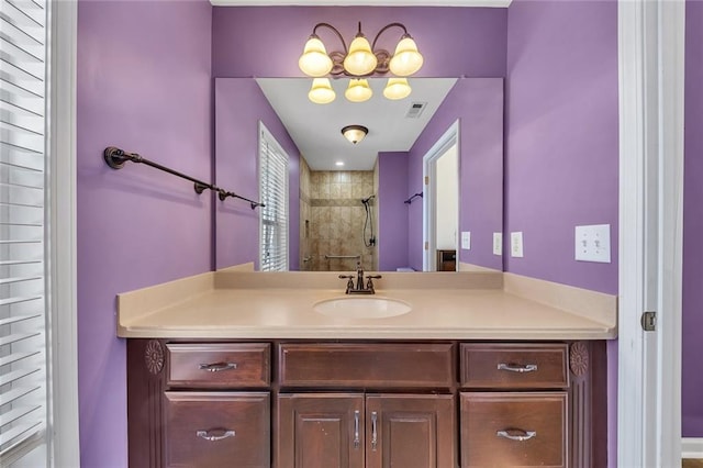 bathroom with visible vents, tiled shower, and vanity