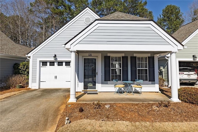 view of front of home featuring a porch, an attached garage, driveway, and roof with shingles