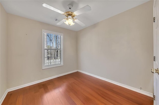 spare room featuring a ceiling fan, wood finished floors, visible vents, and baseboards