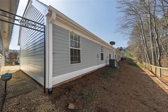 view of side of property featuring central AC unit and fence