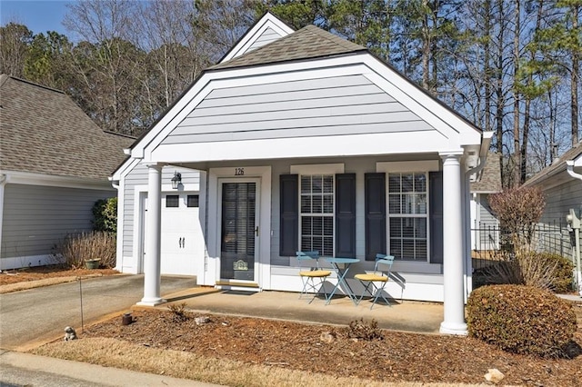 view of front of property featuring covered porch, concrete driveway, and roof with shingles