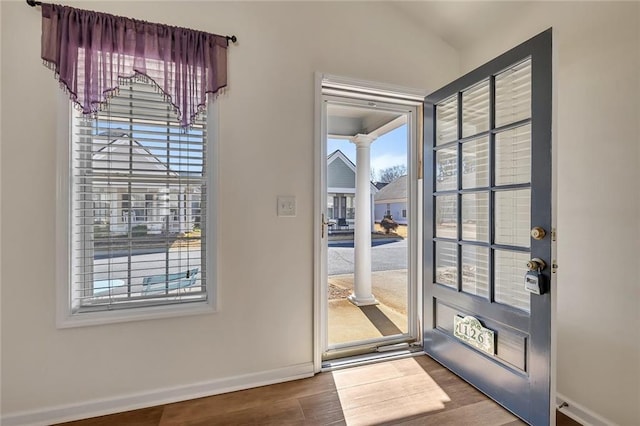 entryway with decorative columns, plenty of natural light, and wood finished floors