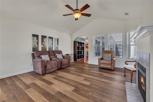 living room featuring visible vents, a fireplace with flush hearth, wood finished floors, arched walkways, and ceiling fan