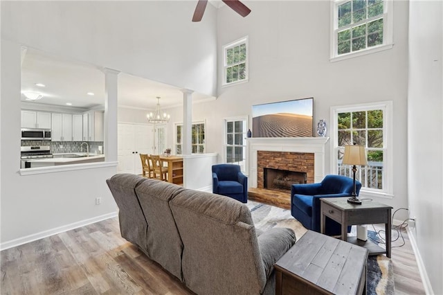 living room featuring light wood-type flooring, decorative columns, a fireplace, and a wealth of natural light