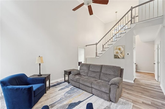 living room featuring stairway, wood finished floors, a towering ceiling, and baseboards