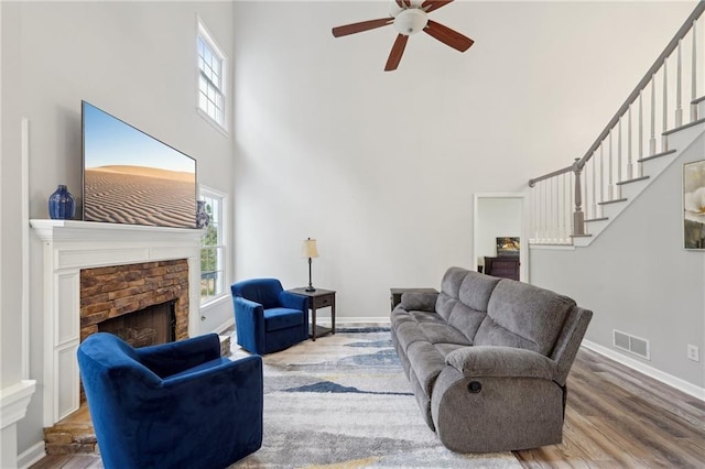 living area with baseboards, visible vents, wood finished floors, stairs, and a stone fireplace