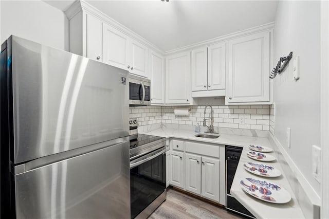 kitchen with appliances with stainless steel finishes, white cabinets, a sink, and decorative backsplash