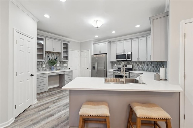 kitchen featuring a peninsula, appliances with stainless steel finishes, a kitchen breakfast bar, and light countertops