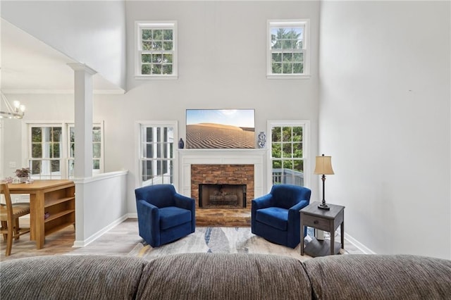 living room with ornate columns, a fireplace, baseboards, and a notable chandelier