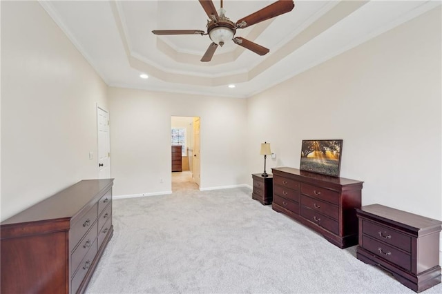 bedroom with baseboards, a raised ceiling, light colored carpet, ensuite bath, and crown molding