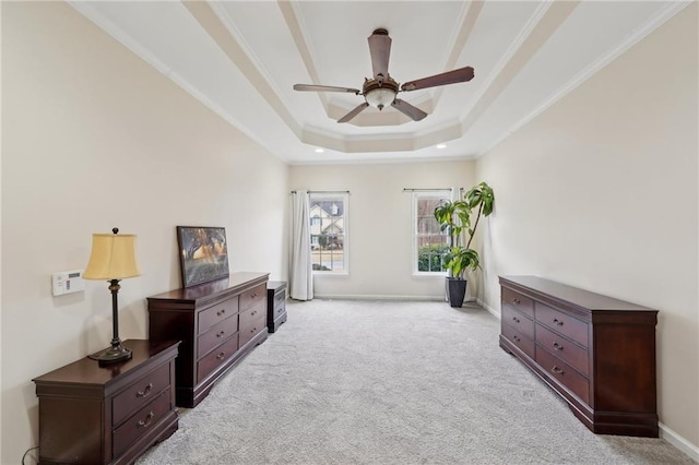 living area featuring baseboards, a ceiling fan, light colored carpet, ornamental molding, and a tray ceiling