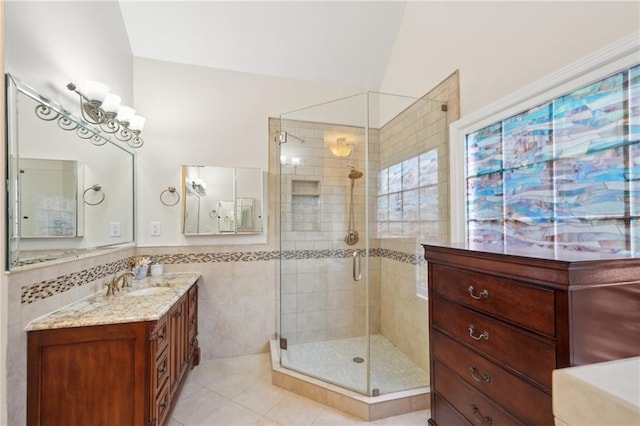 bathroom featuring tile walls, wainscoting, a shower stall, vanity, and tile patterned flooring