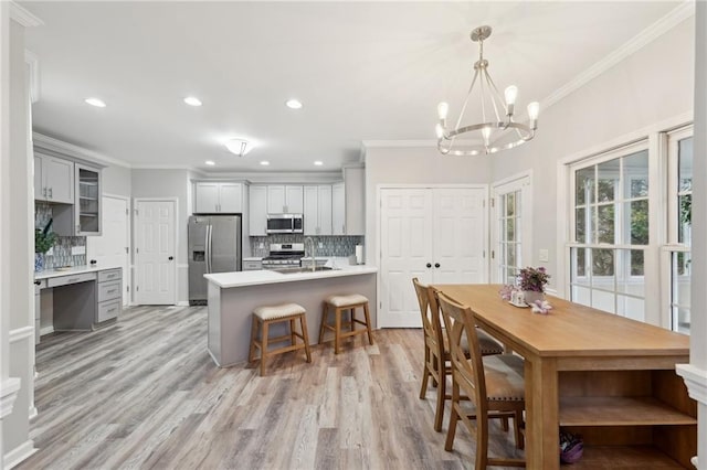 dining space featuring light wood finished floors, ornamental molding, and recessed lighting