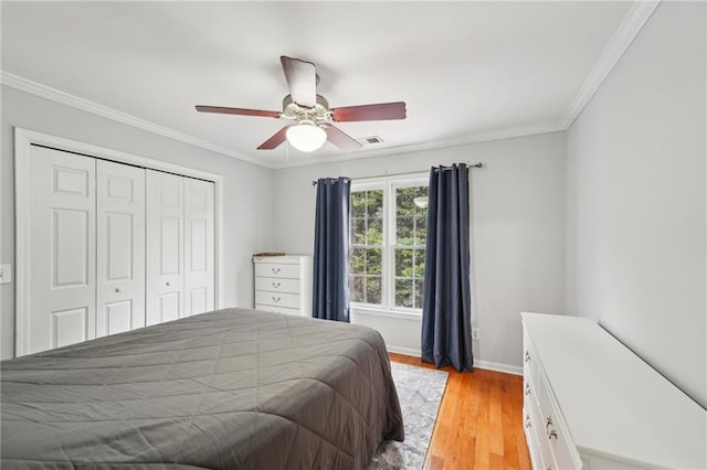 bedroom with crown molding, light wood finished floors, a closet, visible vents, and baseboards