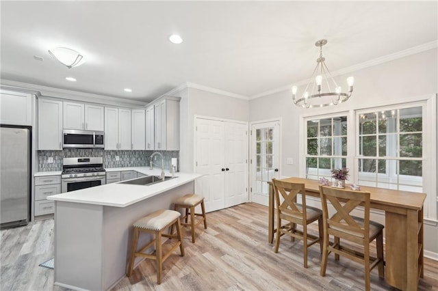 kitchen featuring gray cabinetry, a sink, light countertops, appliances with stainless steel finishes, and decorative light fixtures