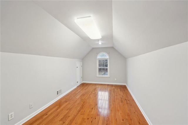 additional living space featuring lofted ceiling, light wood-type flooring, visible vents, and baseboards