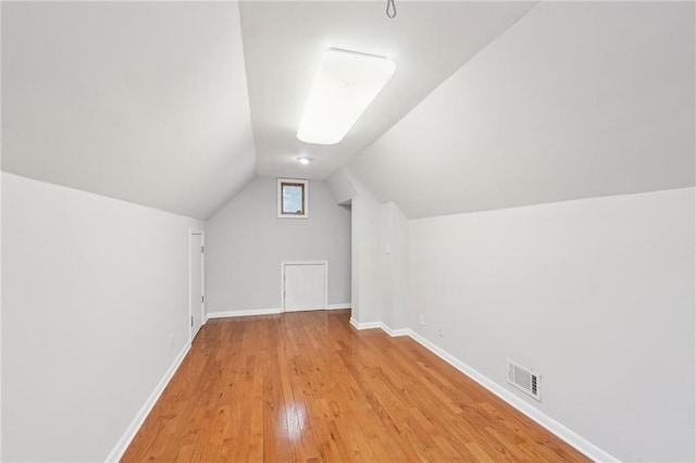 bonus room with lofted ceiling, light wood finished floors, baseboards, and visible vents