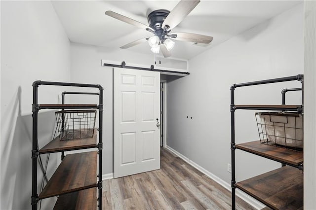 interior space featuring wood finished floors, baseboards, and a barn door