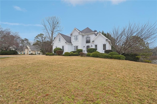 view of front of house featuring a chimney, a front yard, and stucco siding