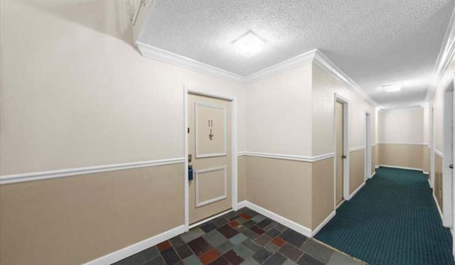 hallway featuring ornamental molding, a textured ceiling, and baseboards