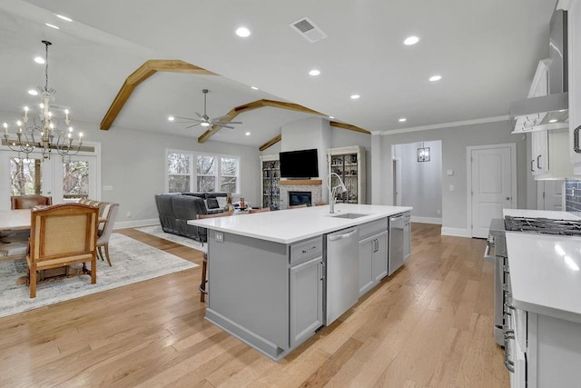 kitchen featuring gray cabinetry, a sink, stainless steel appliances, wall chimney range hood, and lofted ceiling