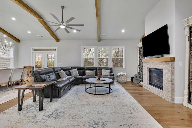 living room featuring visible vents, lofted ceiling with beams, wood finished floors, french doors, and a fireplace