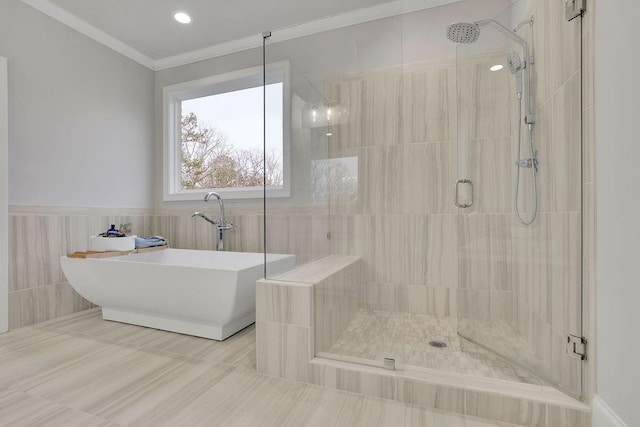 full bathroom with tile patterned flooring, a shower stall, crown molding, a freestanding bath, and wainscoting