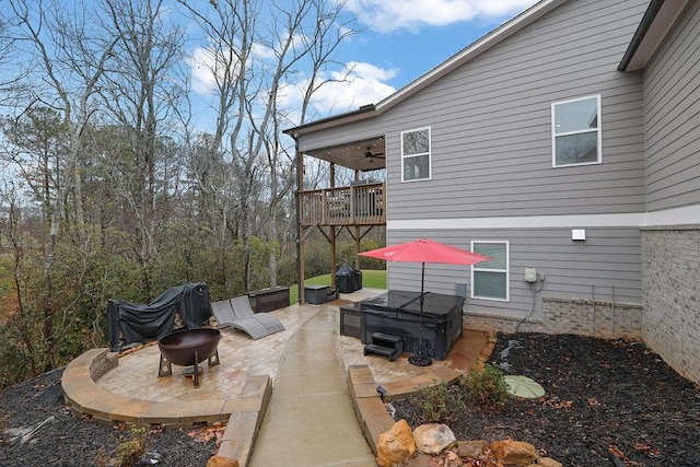 view of patio with ceiling fan, a hot tub, and an outdoor fire pit